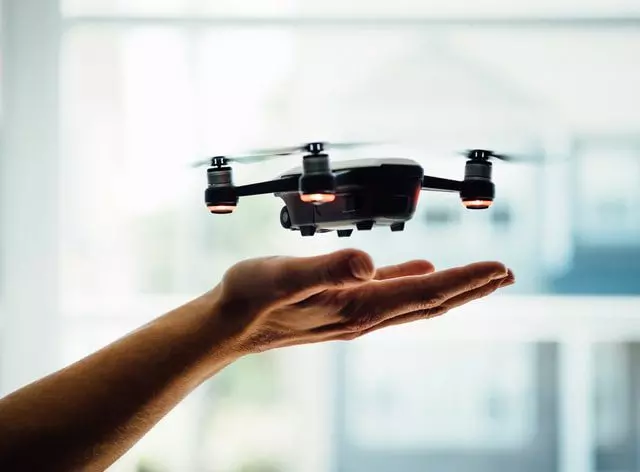 Hovering over an open hand is a tiny drone.