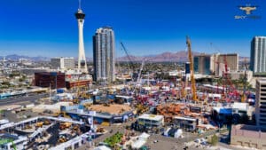 Aerial view of a large outdoor construction expo in Las Vegas, with cranes, equipment displays, crowds, and city buildings—including the Stratosphere Tower—under a clear blue sky. Perfect for any Las Vegas photo gallery.
